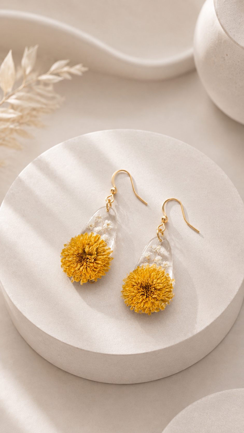 Ohrhänger Goldblüte: gelbe Chrysantheme mit winzigen weißen Blüten in klarem Harz mit vergoldetem Haken auf cremefarbener Keramik